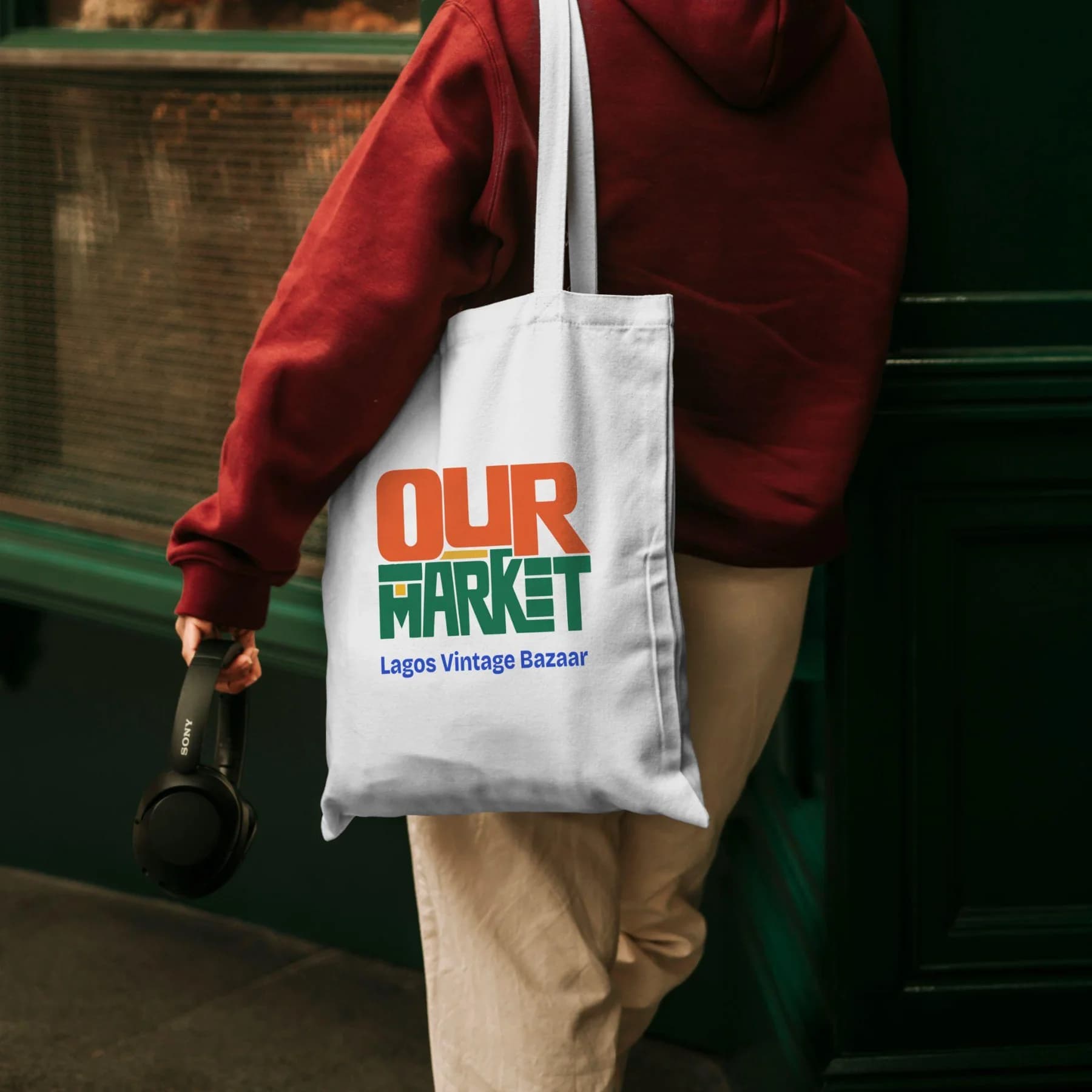 Our Market wordmark on a canvas tote carried by a person in a red top
